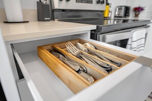 A drawer with utensils inside, part of a kitchen area.