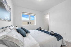 A bedroom with a bed, pillows, a window, and a door.
