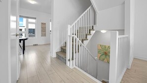 A modern interior with a staircase, a dining area, and a view of the outside.