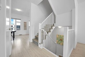 A modern interior with a staircase, a dining area, and a view of the outside.
