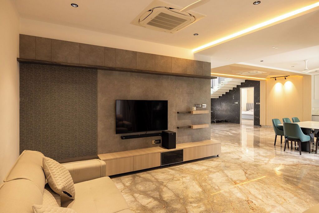 A modern living room with a flat-screen TV, built-in shelves, a sofa, and a dining area with chairs.