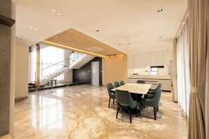 Ein moderner Essbereich mit Marmorboden, einer Treppe und einer Küche im Hintergrund.