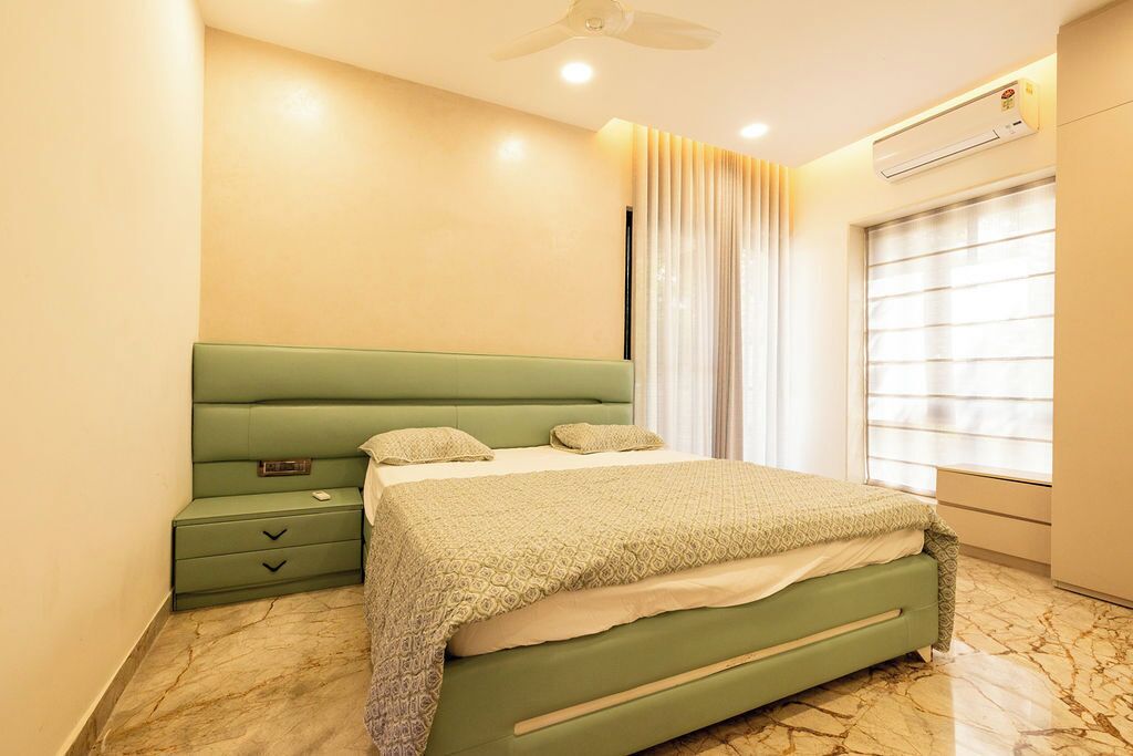 A bedroom with a green bed, a nightstand, a window with curtains, and an air conditioning unit.