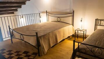 Un dormitorio con cama, mesita de noche, una silla, alfombra estampada y una escalera.