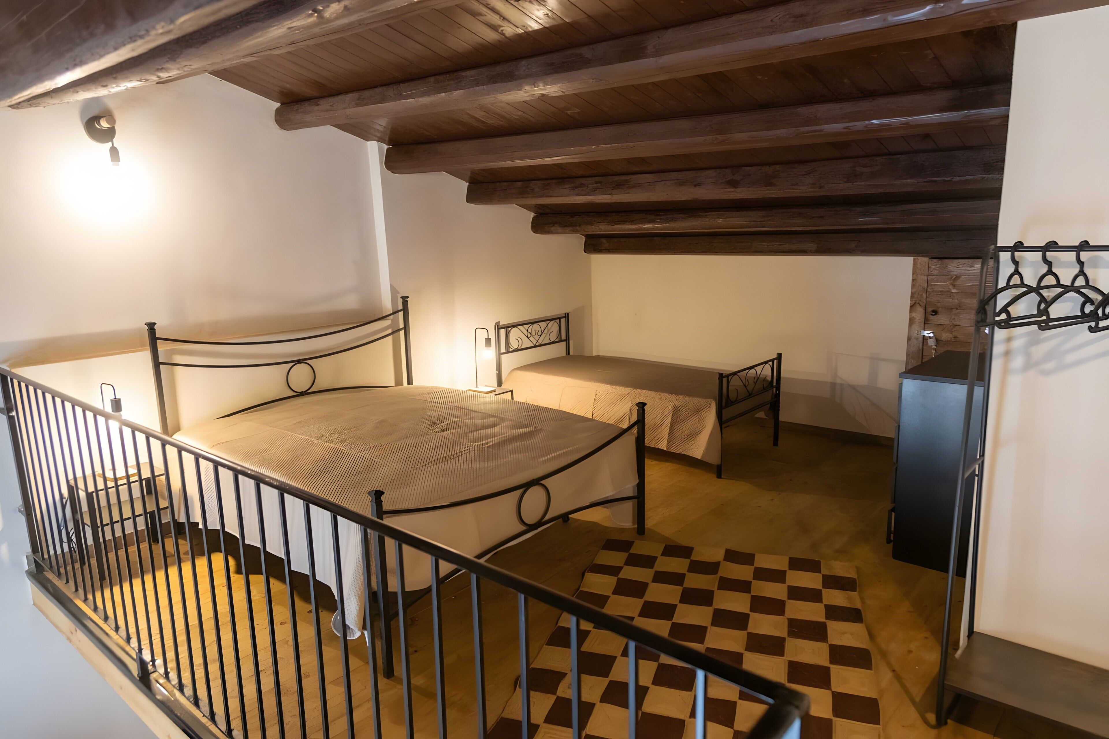 A bedroom with a bed, a bedside table, a wardrobe, and a checkered floor.