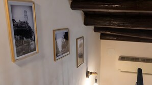 A wooden staircase with white walls and a ceiling with exposed beams. There are three framed pictures on the wall.