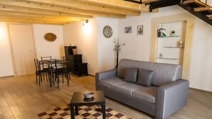 A living room with a sofa, a dining table with chairs, a coffee table, and a patterned rug.