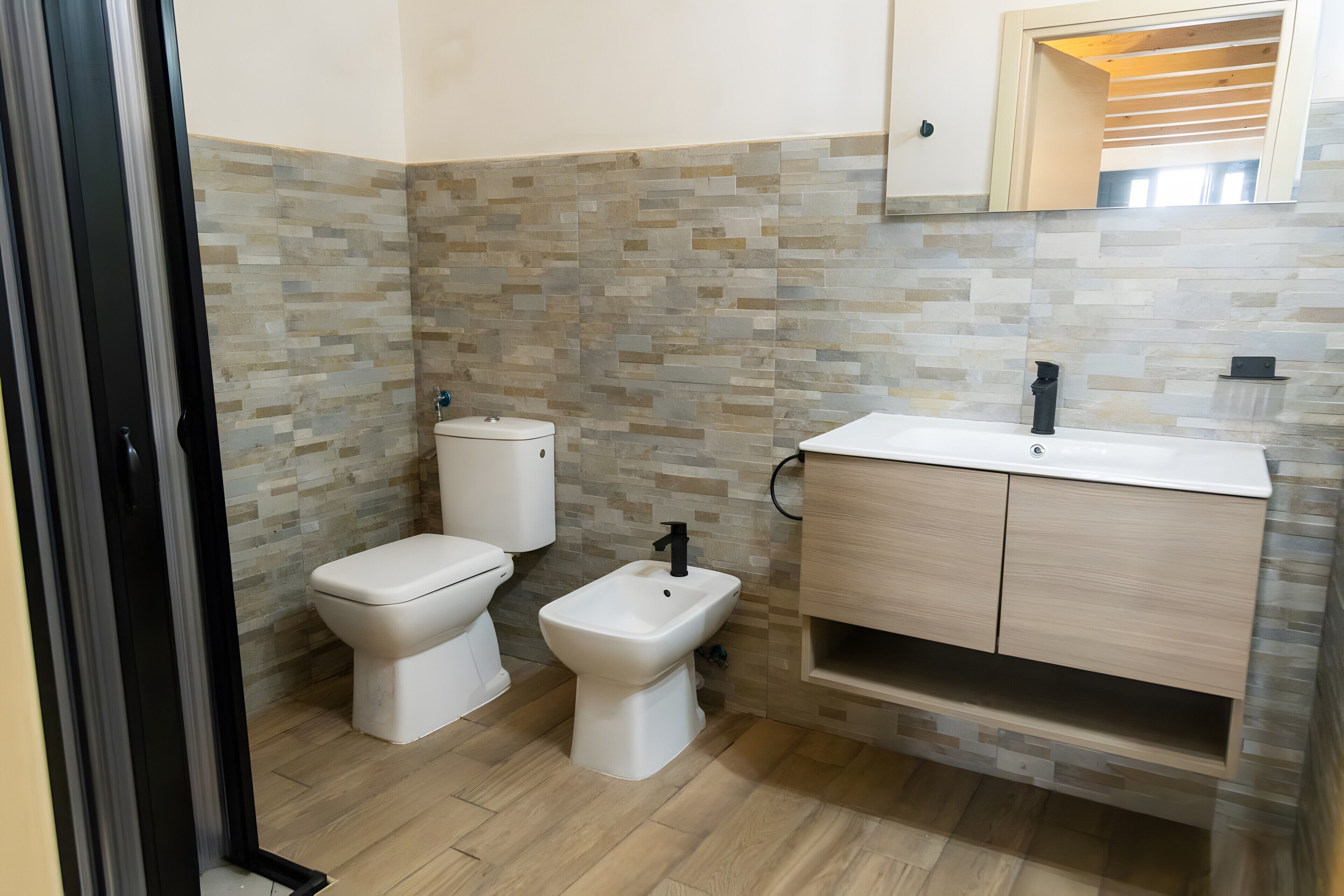 A bathroom with a toilet, bidet, and a sink with a cabinet.