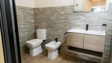 A bathroom with a toilet, bidet, and a sink with a cabinet.