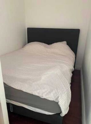 Ein Bett mit dunkelbrauner Kopfteil und weiß gestreifter Bettdecke.
