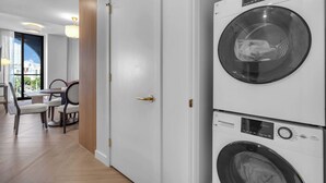 Ein Hotelzimmer mit Essbereich, Blick auf die Stadt und einer gestapelten Waschmaschine und einem Trockner.