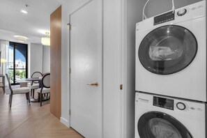 A hotel room with a dining area, a view of the city, and a stacked washer and dryer. - Wynwood Luxury Atelier Resort (Miami)