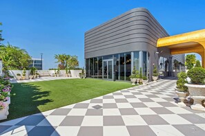 A modern building with a checkered outdoor patio, a grassy lawn, and various potted plants. - Wynwood Luxury Atelier Resort (Miami)