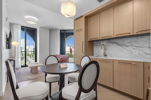 Eine moderne Küche mit Holzschränken, einer Marmorarbeitsplatte und einem Essbereich mit rundem Tisch und Stühlen.