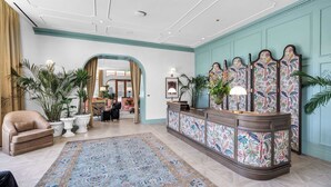 Eine Hotelhalle mit einer Rezeption, einer Sitzecke und Blick in die Zimmer.