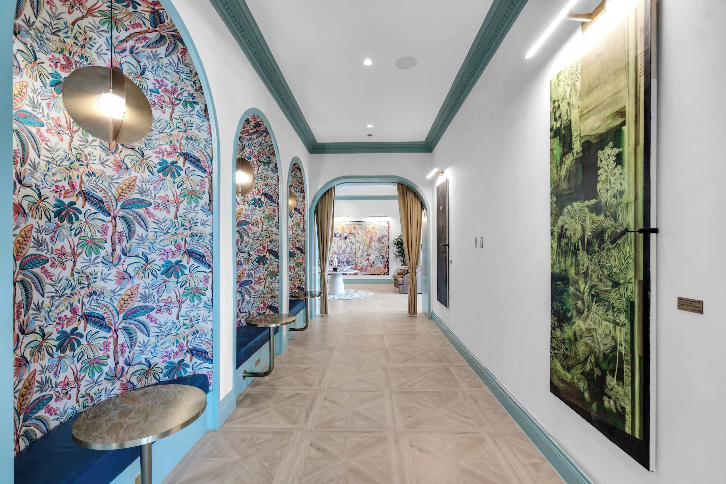 A hallway with floral wallpaper, a round table, and a large painting on the wall.