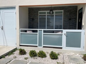 A modern building with a garage door, a balcony with a glass enclosure, and a stone wall with a window. - Gorgeous 3-bedroom apartment with AC and pool in vibrant Isabela (Isabela)