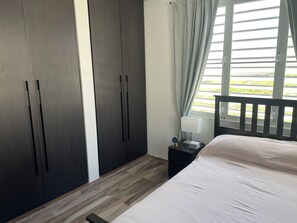 A bedroom with a bed, a nightstand, a lamp, and a window with curtains. - Gorgeous 3-bedroom apartment with AC and pool in vibrant Isabela (Isabela)