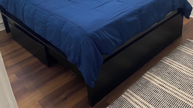 Una camera da letto con un letto grande, un comodino, tende e mensole a parete con oggetti decorativi.
