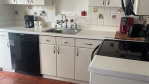 Una cucina con mobili bianchi, lavastoviglie, lavello e tostapane.