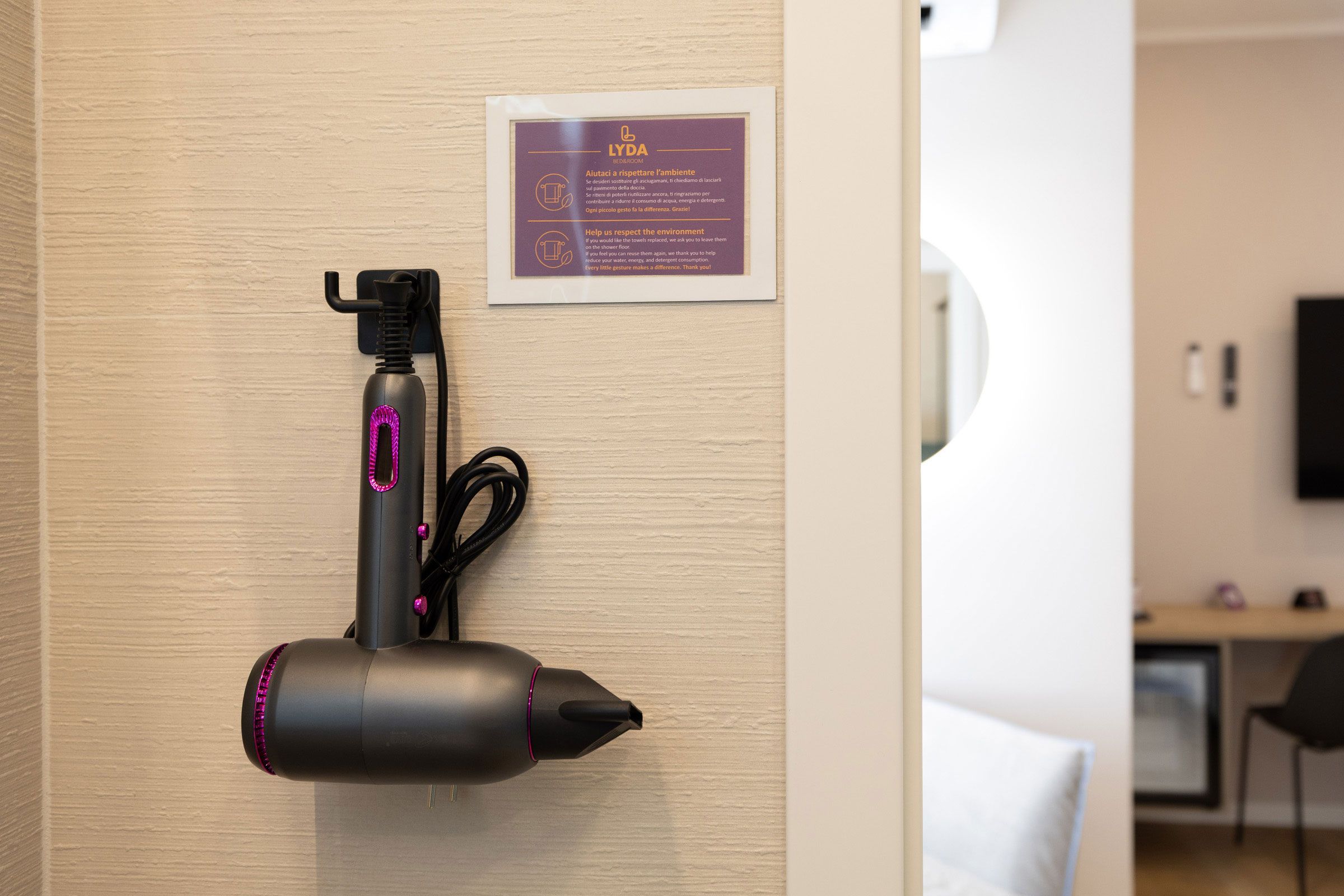 Un sèche-cheveux fixé au mur, avec une pancarte au-dessus.