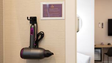 Un sèche-cheveux fixé au mur, avec une pancarte au-dessus.