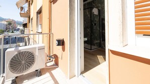 A residential building with a balcony, an air conditioning unit, and a glass door leading to an interior space. - Lyda Bed&Room (La Spezia)