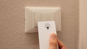 A hand holding a card with a symbol, in front of a switch on a wall. - Lyda Bed&Room (La Spezia)