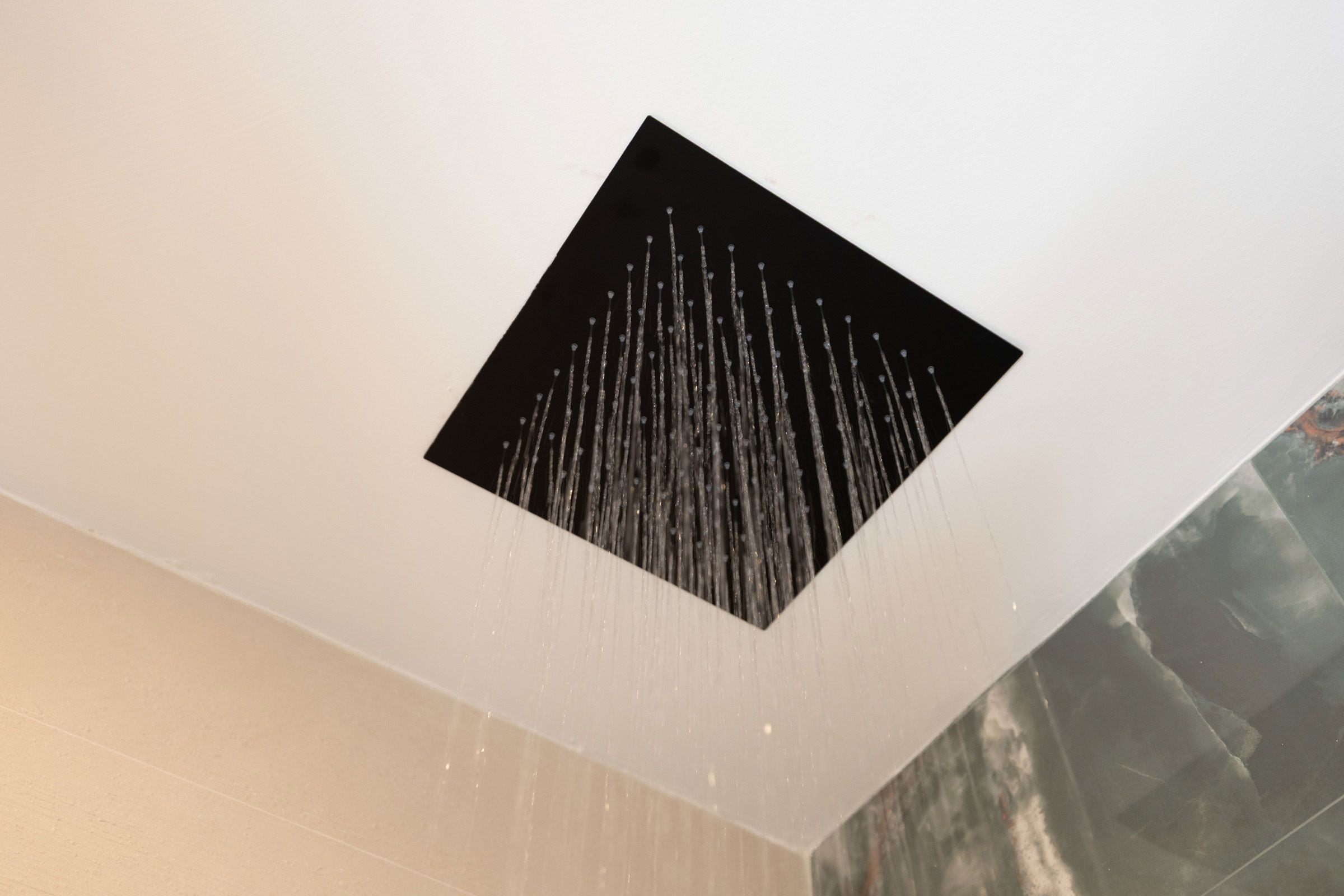 A ceiling with a square opening allowing water to flow down.