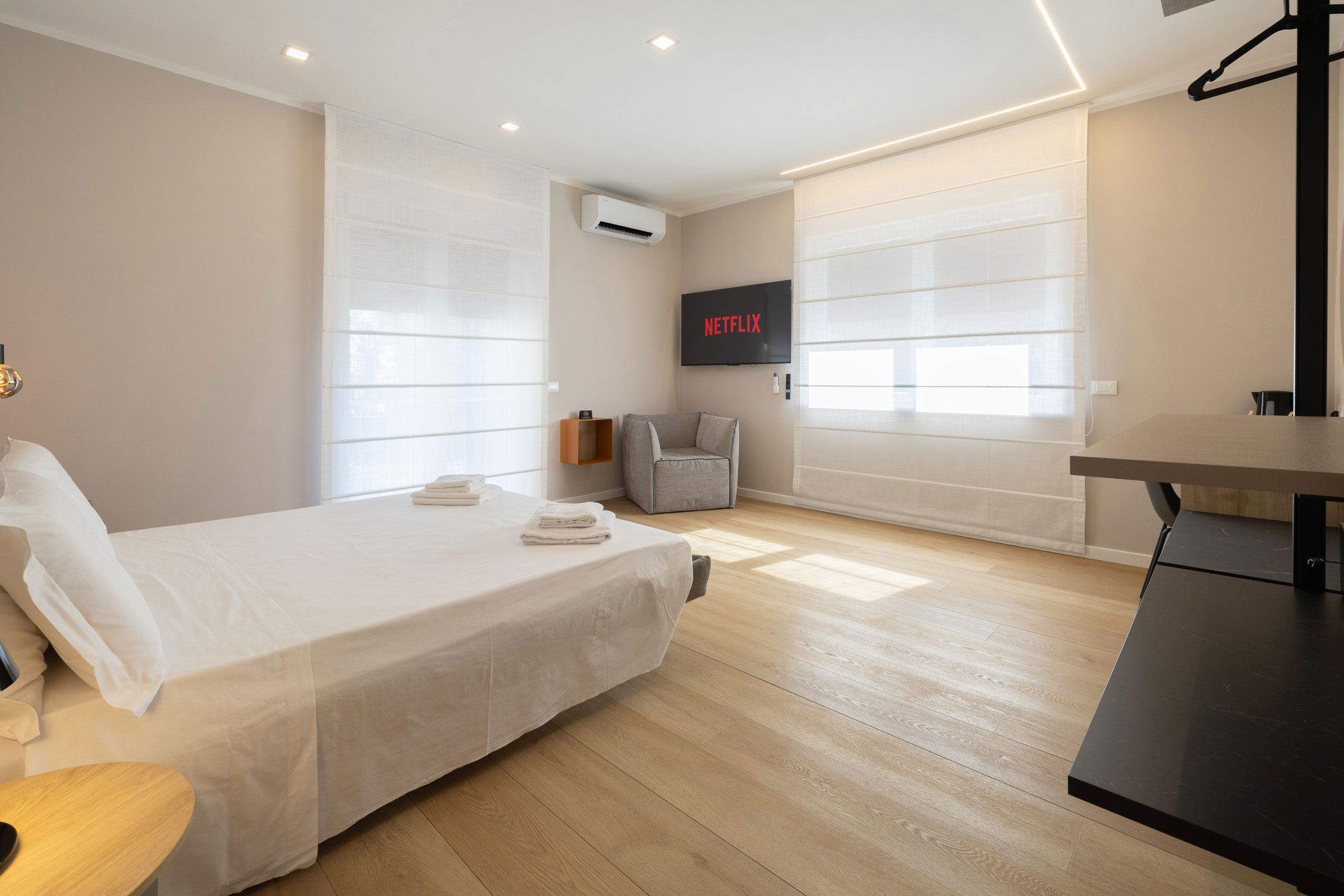 Un dormitorio moderno con una cama, un escritorio y un televisor montado en la pared.