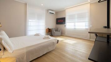 Un dormitorio moderno con una cama, un escritorio y un televisor montado en la pared.