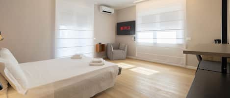 Un dormitorio moderno con una cama, un escritorio y un televisor montado en la pared.