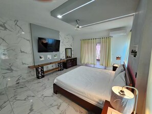 Ein modernes Schlafzimmer mit einem großen Bett, einem an der Wand montierten Fernseher, einer Bank und einer Kommode.
