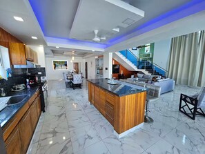A modern kitchen with a marble floor, wooden cabinets, and a central island. - Villa Dominicana Puerto Plata (Puerto Plata Province)
