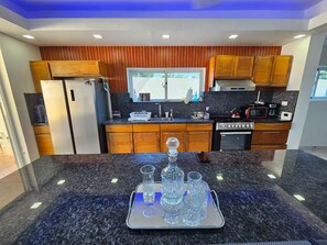 A modern kitchen with wooden cabinets, granite countertops, and stainless steel appliances. - Villa Dominicana Puerto Plata (Puerto Plata Province)