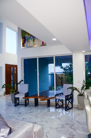 A spacious living area with a large window, a blue partition, and a wooden bench. - Villa Dominicana Puerto Plata (Puerto Plata Province)
