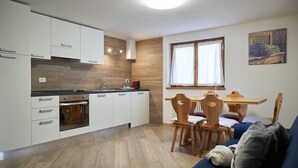 Una cucina moderna con mobili bianchi, un piano di lavoro in legno e un'area pranzo con tavolo e sedie in legno.