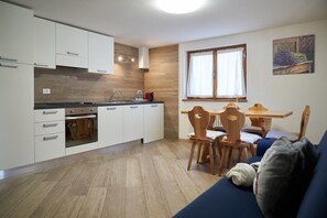 Eine moderne Küche mit weißen Schränken, einer Holzarbeitsplatte und einem Essbereich mit Tisch und Stühlen.