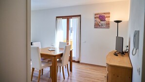 Un'area pranzo con un tavolo e sedie in legno, un quadro appeso al muro e una lampada su un mobile in legno.
