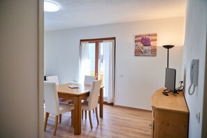 Ein Essbereich mit einem Holztisch und Stühlen, einem Bild an der Wand und einer Lampe auf einer Holzkommode.