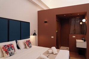 Ein modernes Hotelzimmer mit Bett, Nachttischlampe, Badezimmer mit Spiegel und Waschbecken.