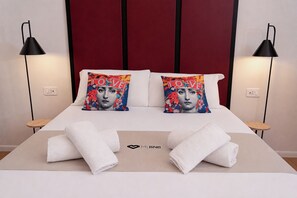Ein ordentlich bezogenes Bett mit zwei Kissen, zwei Nachttischen und einem Logo auf der Tagesdecke.
