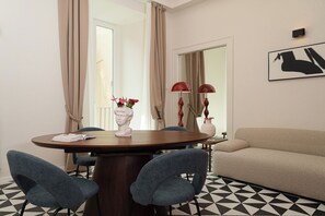Ein Essbereich mit einem runden Tisch, zwei Stühlen, einer Blumenvase und einer Couch.