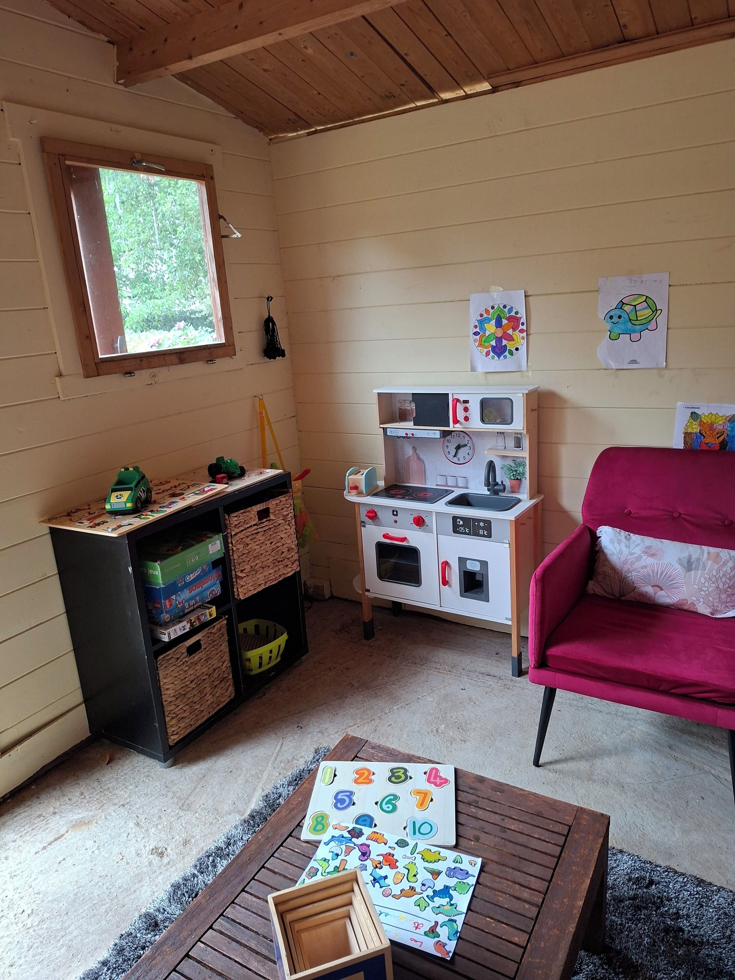 A room with a play kitchen, a red chair, and educational toys.
