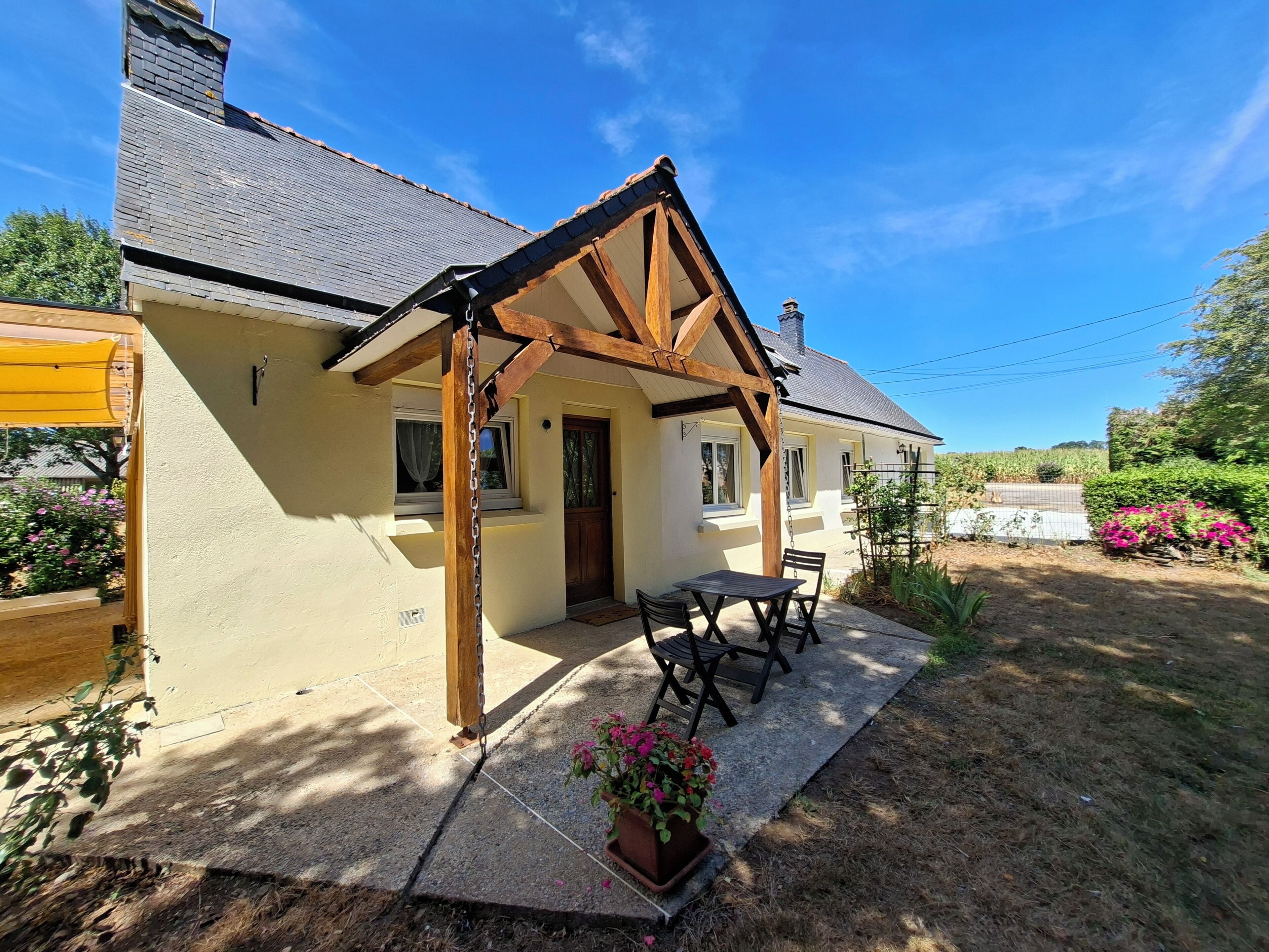 Une maison avec un patio couvert, une porte et une fenêtre.