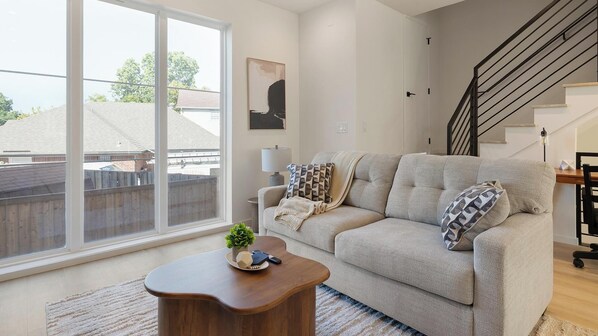A living room with a sofa, a coffee table, and a staircase. - Landing Amazing 3BD in Dallas (Dallas)