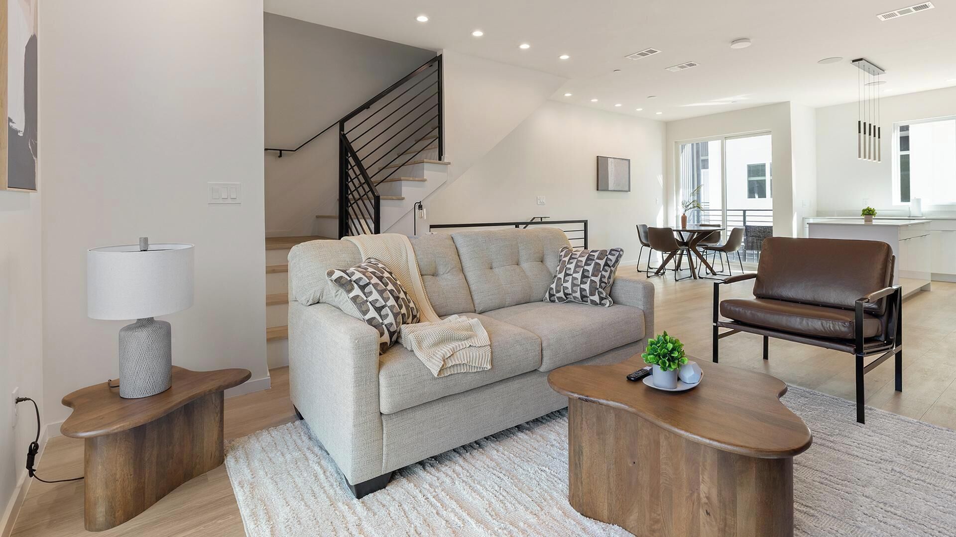 Un salon moderne avec un canapé, des fauteuils, une table basse et une lampe.