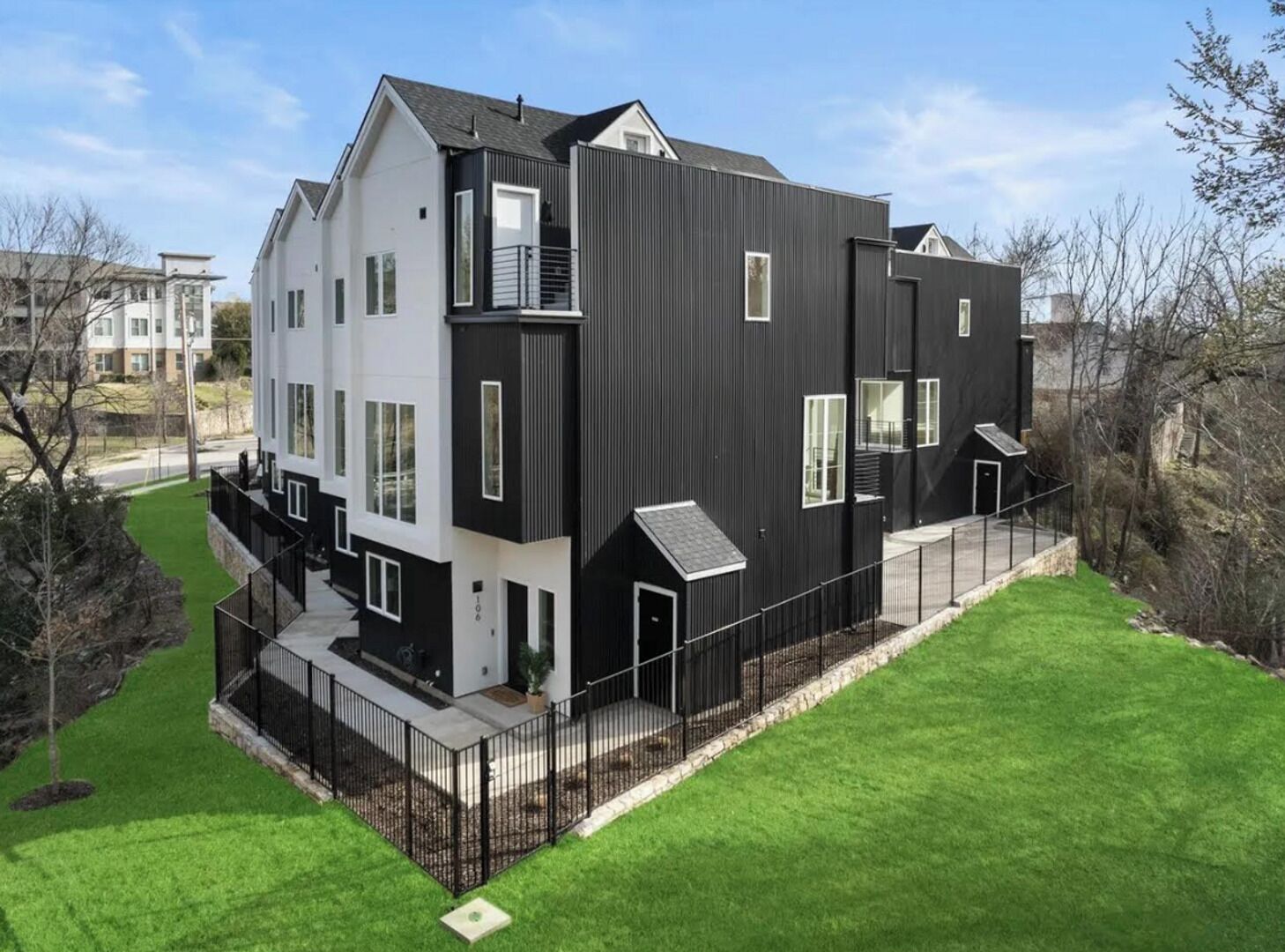 Een modern woongebouw met twee verdiepingen, een plat dak, grote ramen en een zwart-wit gevel.
