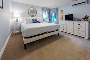 Un dormitorio con cama, televisión, cómoda y espejo.