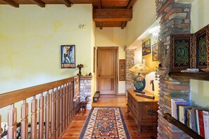 Un corridoio con una scala in legno, un muro in pietra e una libreria piena di libri.